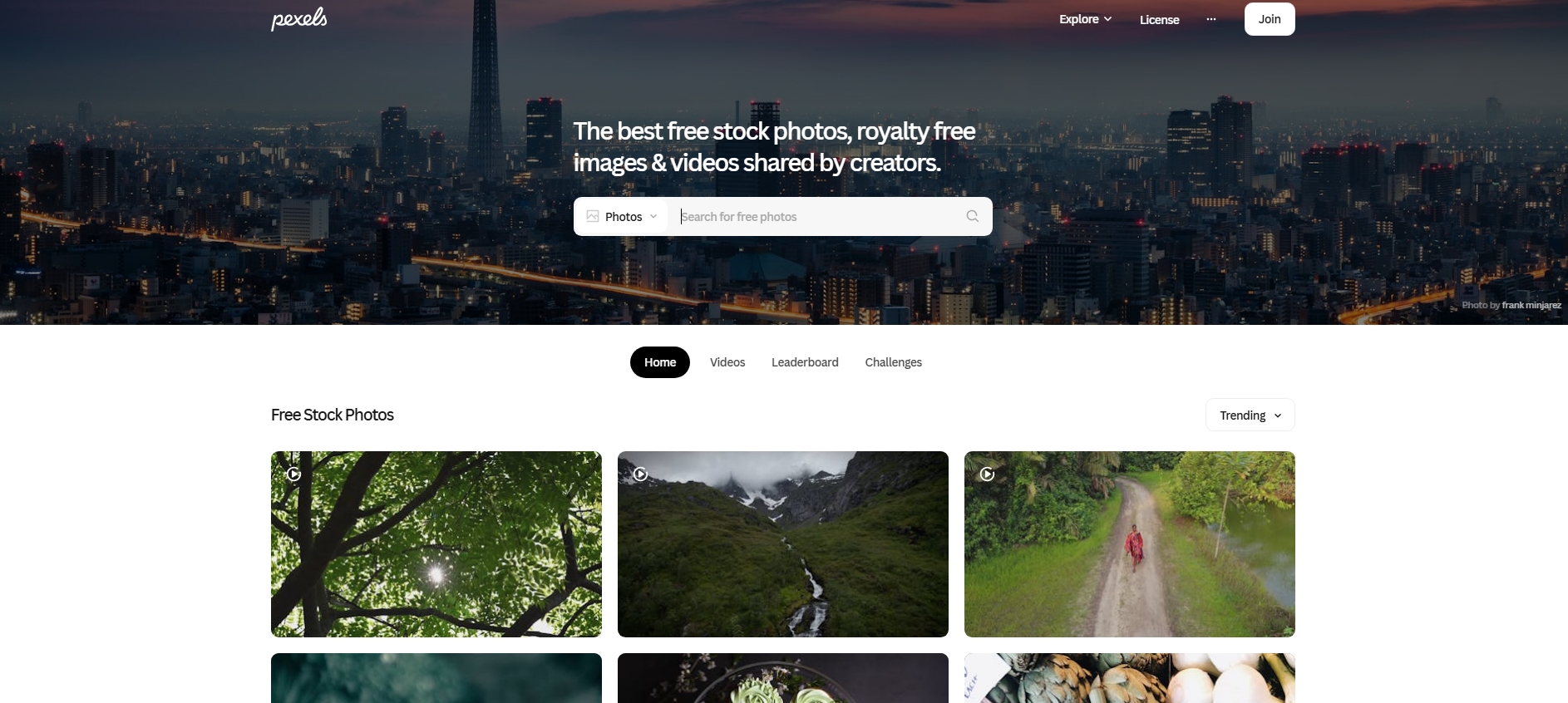 Pexels homepage showcasing free stock images and search bar over a cityscape background