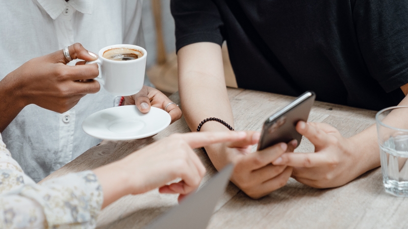 People gathered around a table looking at a phone, showing community-focused engagement on social media