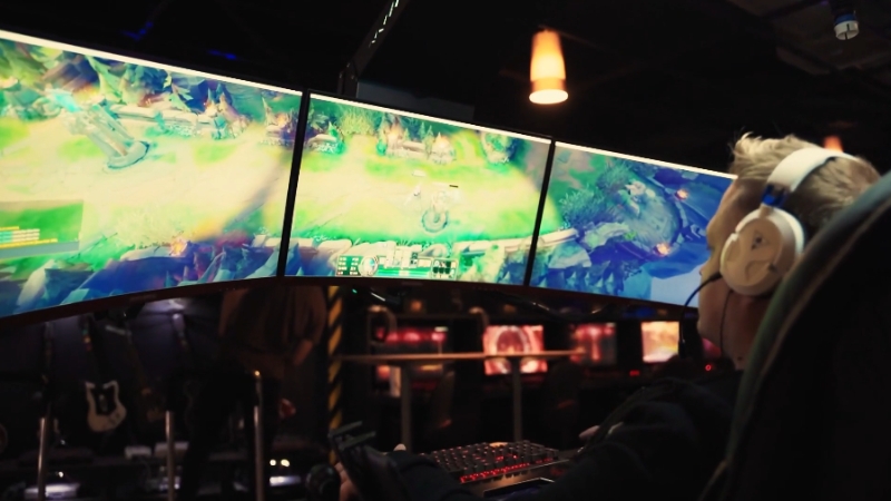 A gamer uses a triple-monitor setup, showing how good UX in video games improves the whole experience