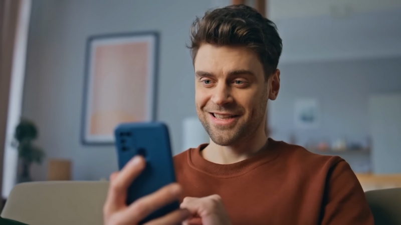 A man smiles while looking at his phone, representing a confident and professional approach to creating an Instagram bio for personal branding