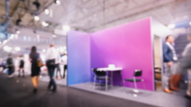 A colorful exhibition booth setup at a large-scale event with people walking nearby