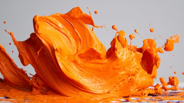 Bright orange paint splashing across a surface, used to represent energy and action in digital marketing visuals