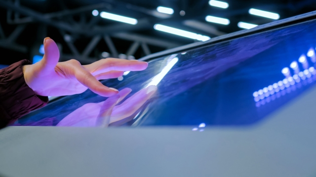 A person interacts with a large touchscreen display at an event booth