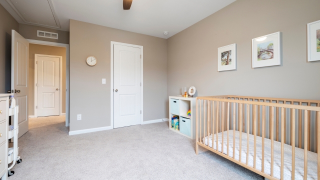 A cozy baby nursery with a wooden crib, neutral walls, and soft carpet flooring