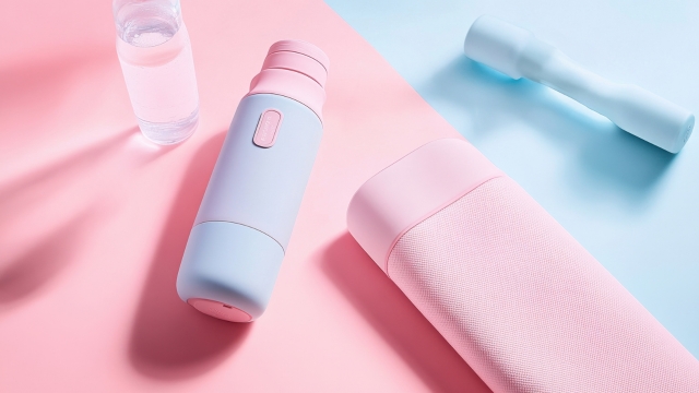 A pastel-colored water bottle, yoga mat, and dumbbell arranged on a pink and blue background