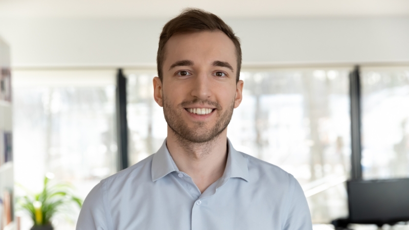 Man smiling with a relaxed expression in a bright office setting