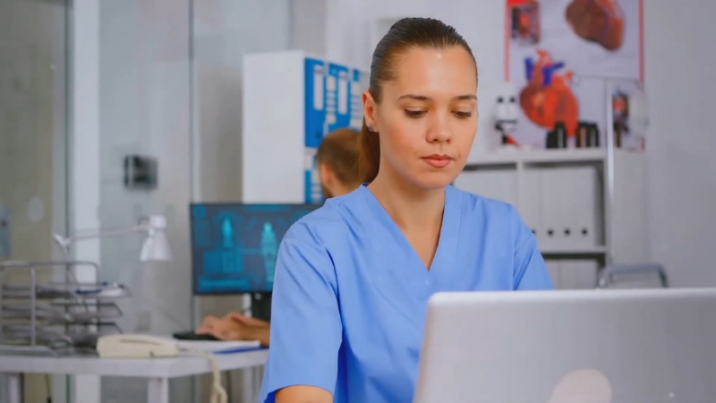 A healthcare professional works on a laptop as part of remote staffing and training support