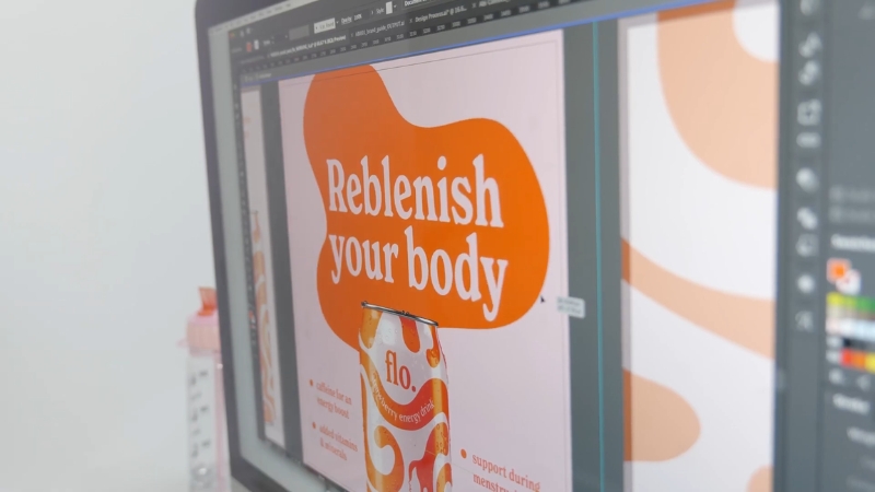 Designer editing a beverage ad layout on a computer screen as part of a visual marketing workflow