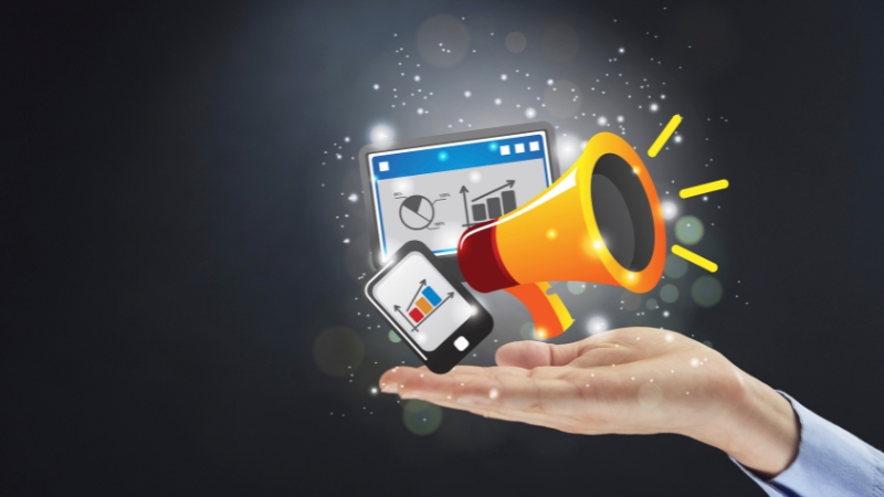 Hand holding a megaphone with a smartphone and analytics dashboard icons representing visual marketing tools