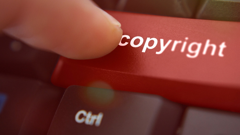 Finger presses a keyboard key labeled copyright, symbolizing legal protection for digital artwork
