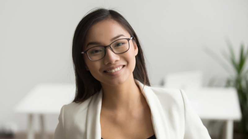 Woman in blazer and glasses against a clean background for a professional headshot