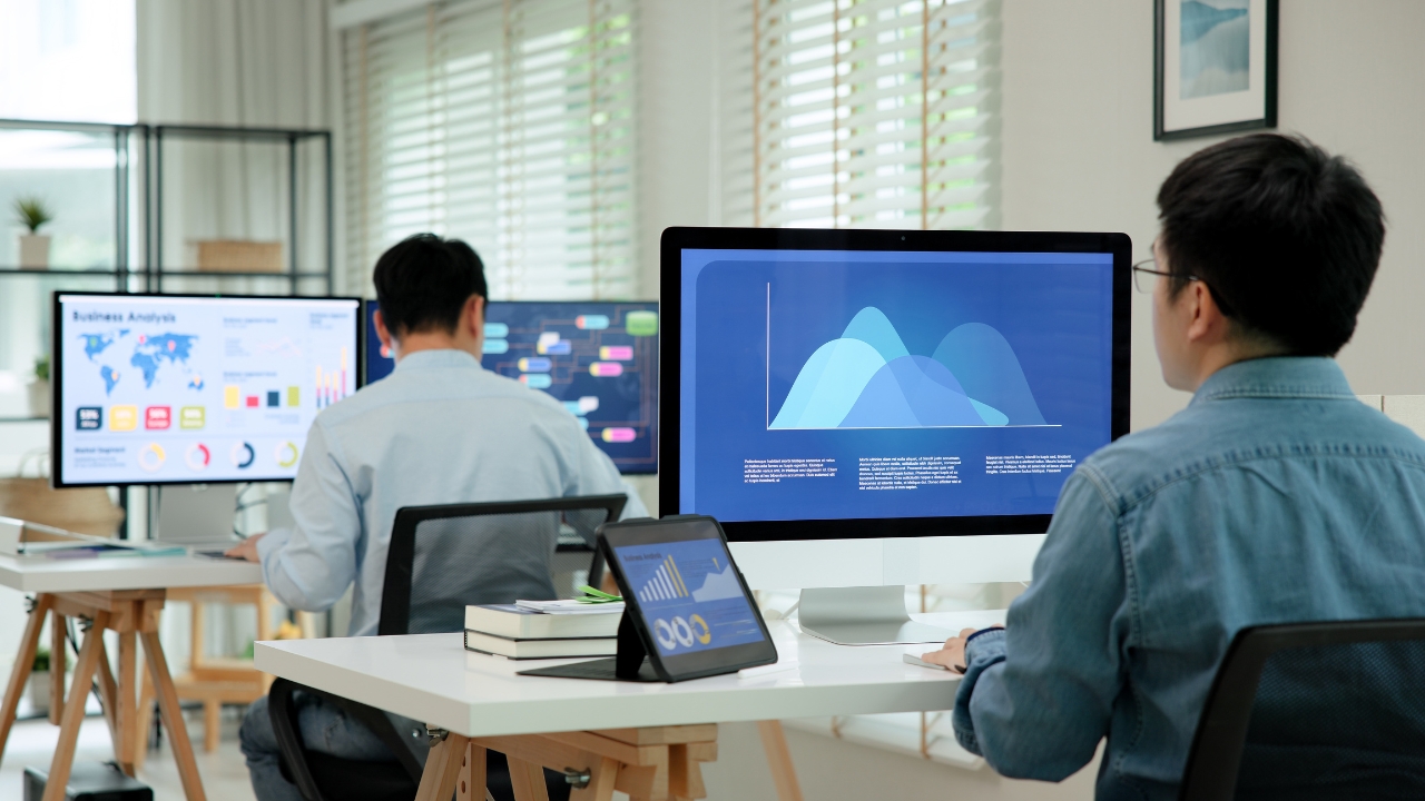Team members review data dashboards on computers in an office using STEM skills