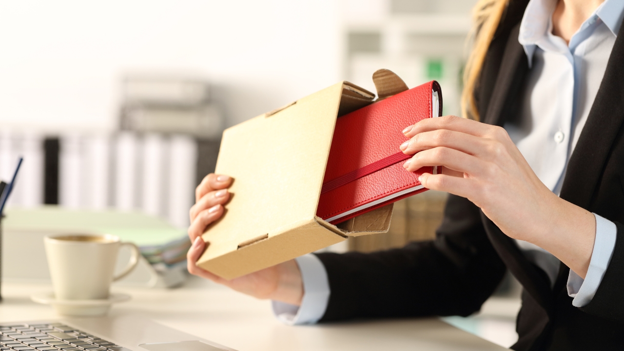 Woman opens a red corporate gift at an office desk