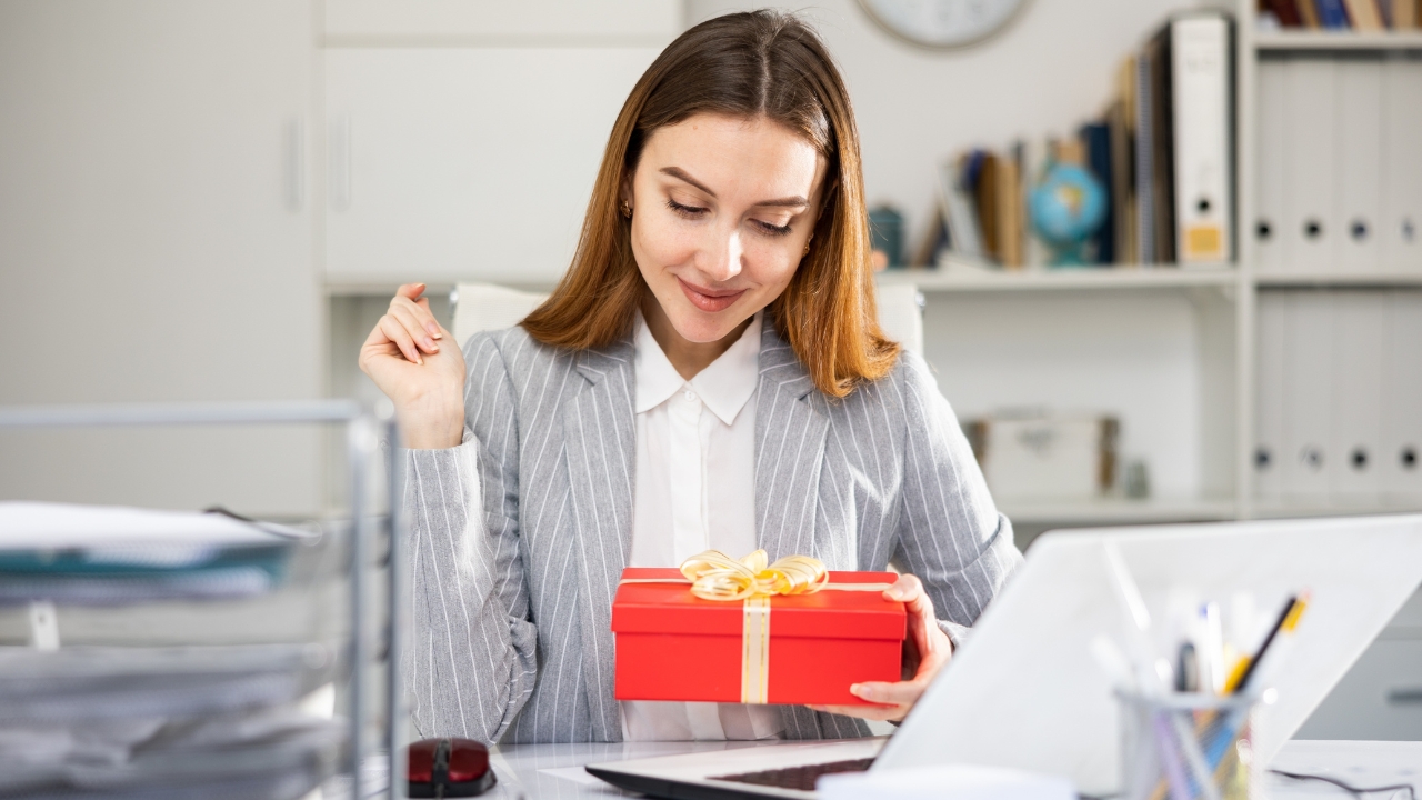 Woman smiles at a gift box on her office desk