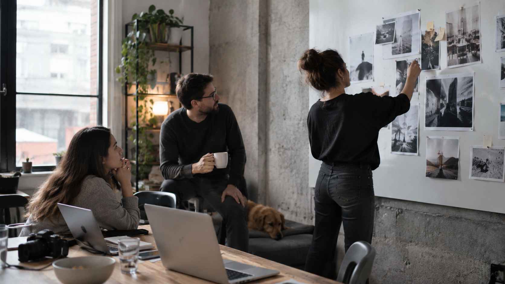 Three creative professionals reviewing campaign images on a studio wall.